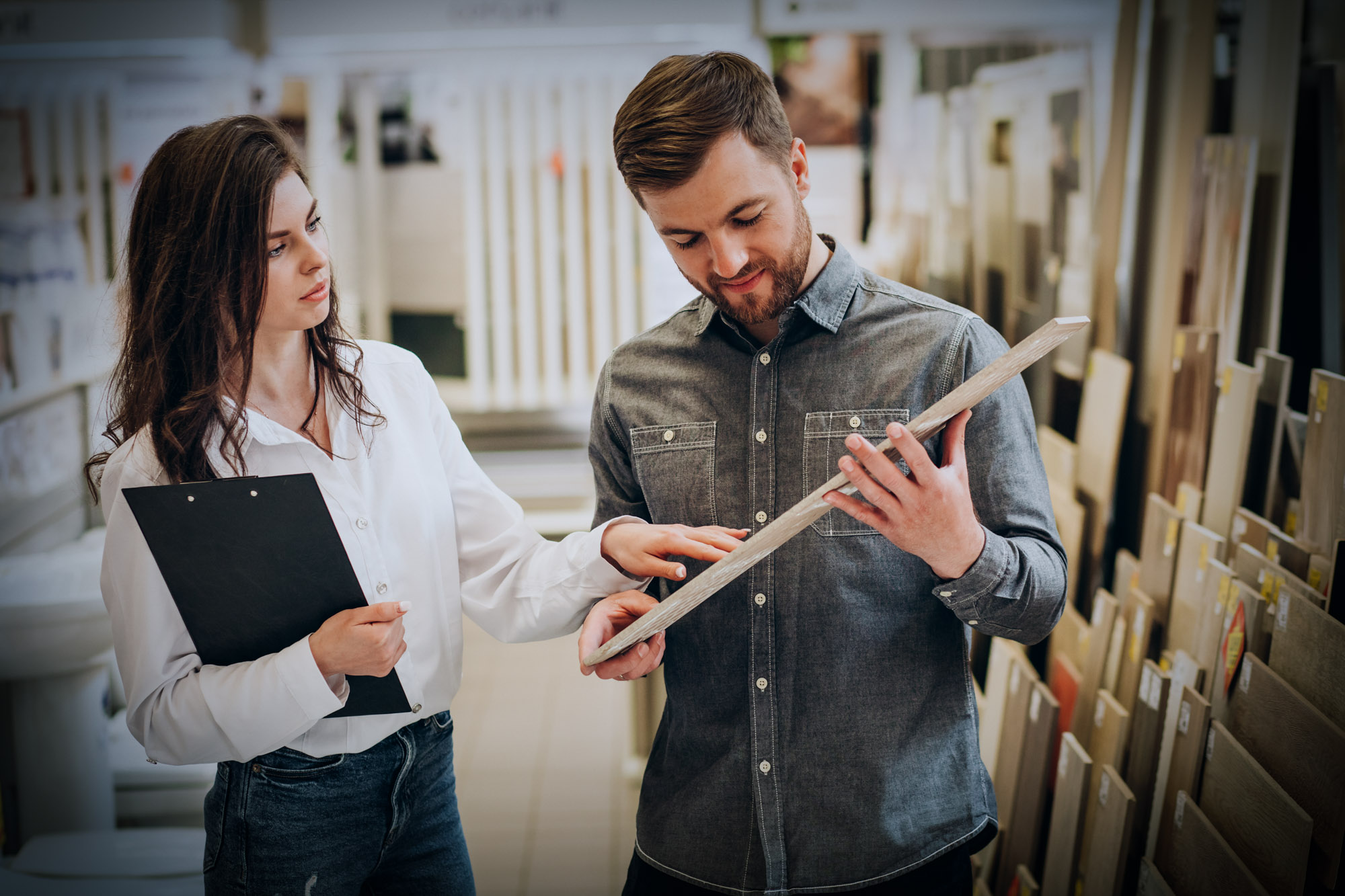 Young man with sales woman choosing tiles at building market